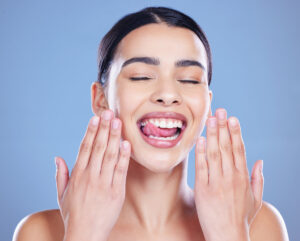 Dental, results and woman with smile in studio for oral hygiene, healthcare and mouth wellness. Happy, client and hands with tongue out for teeth whitening, treatment and cosmetics on blue background.